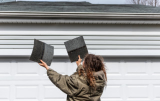 Woman holding up shingles trying to determine where they came from.