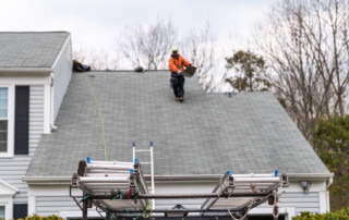 House during day over garage with truck, gray color Single Family Home and man walking on roof shingles and ladder during repair