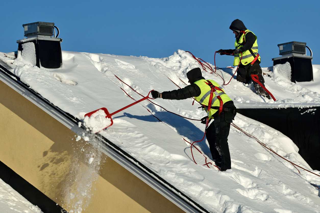 Men cleaning snow off a roof