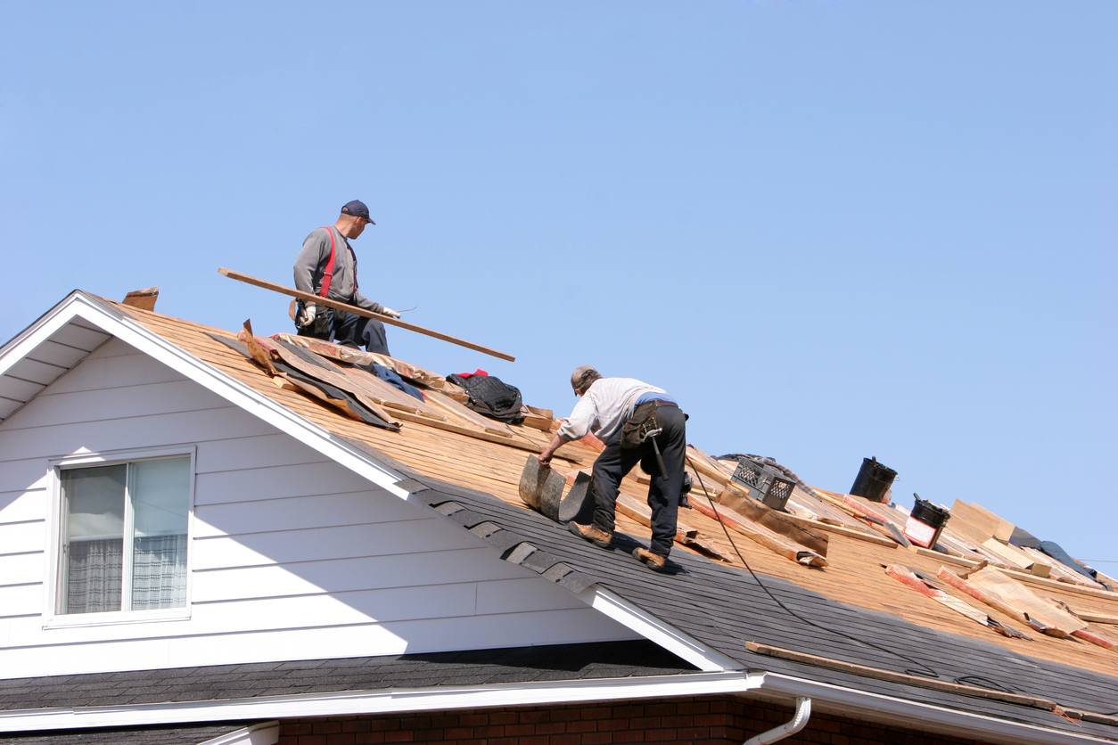 workers replacing shingles on a roof